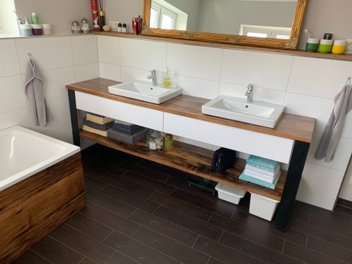 Modernes Badezimmer mit Doppelwaschtisch, Holzregal und freistehender Badewanne.